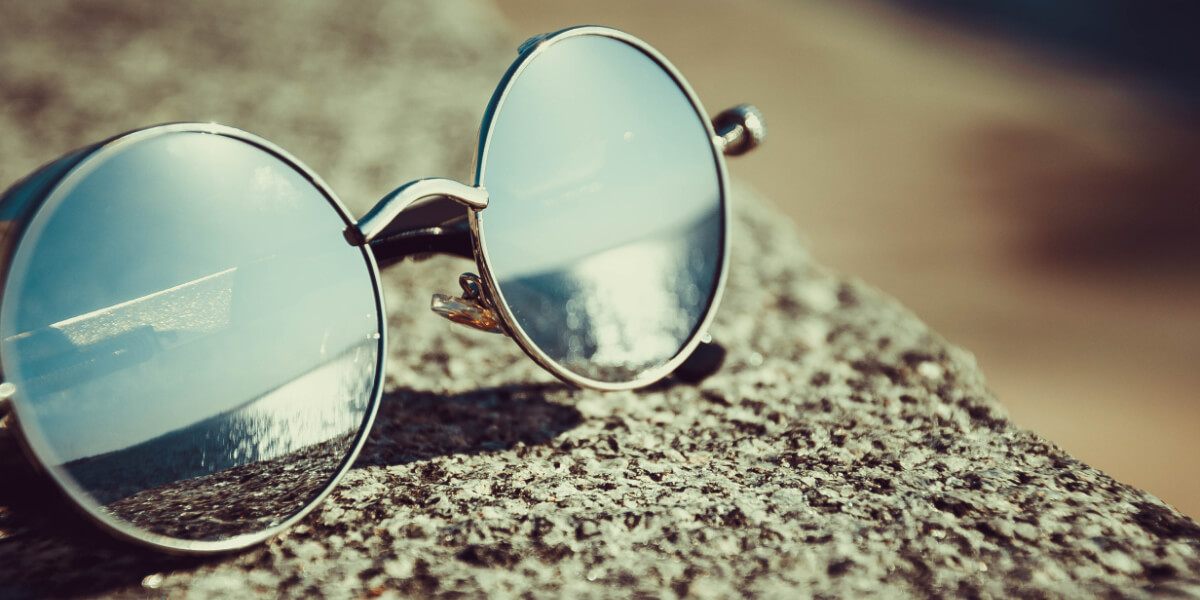Round Sunglasses resting on a grey wall